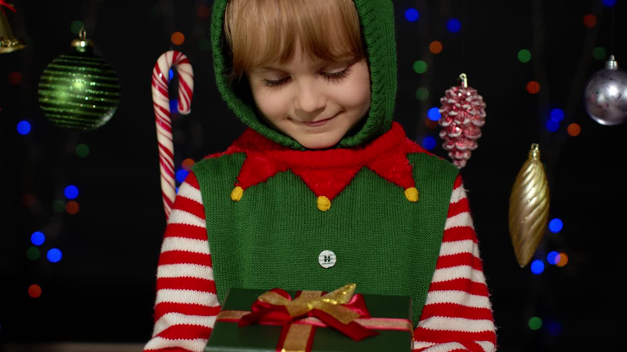 Holčička v kostýmu vánočního skřítka pomocníka Santa Clause dostává překvapivou dárkovou krabici, štěstí.