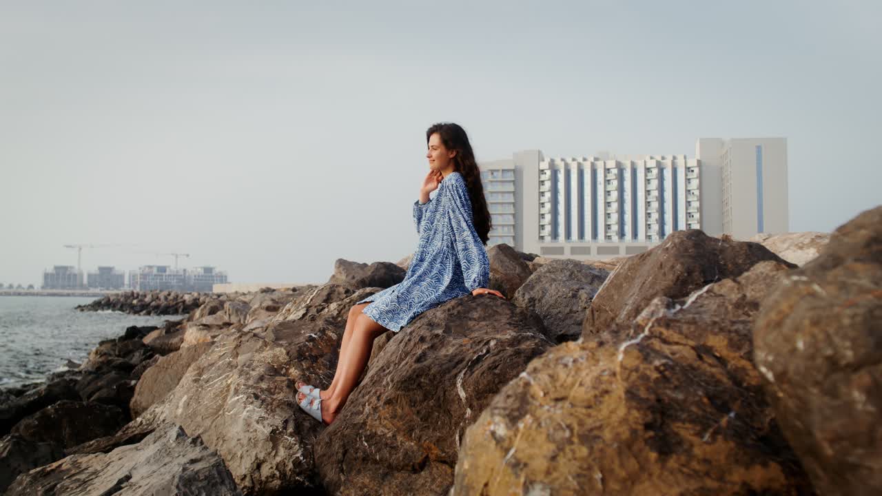 Woman Sitting on Rocks by the Sea