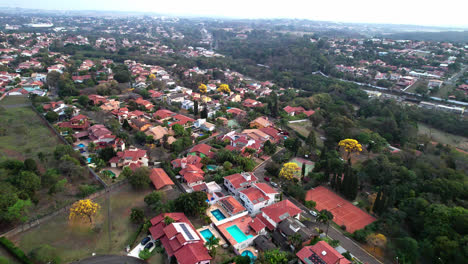 Barrio-Suburbano-Elevado,-Vista-Superior-De-Los-Tejados-De-Las-Casas-Entre-La-Vegetación-Con-Manchas-De-árboles-Amarillos,-Volando-Hacia-Adelante