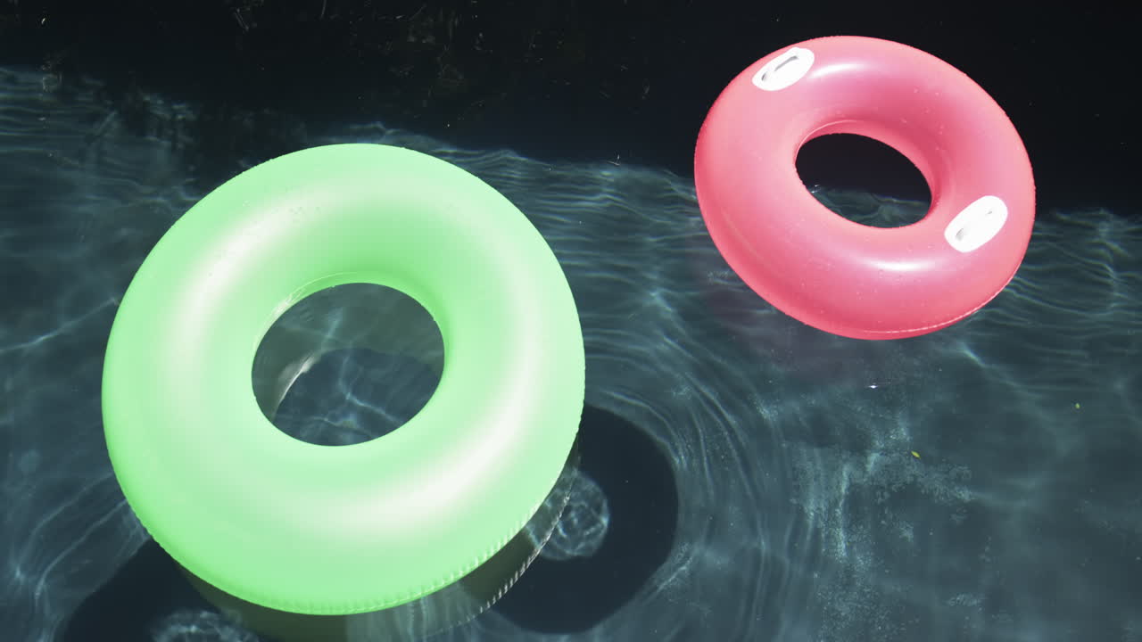 dos anillos de natación coloridos flotan en la superficie de una piscina