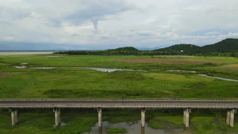 aerial footage towards a fantastic video revealing a car, elevated railway, waterways, farmlands, hills and a lake