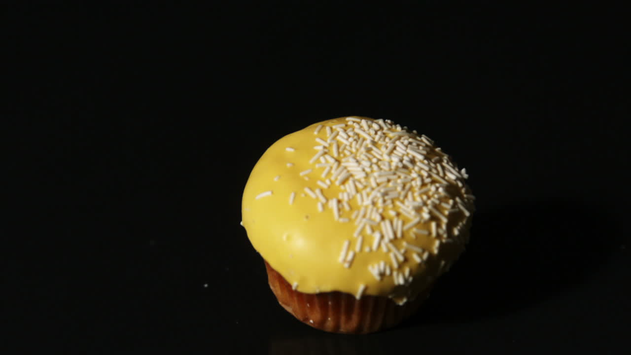 Cupcake giallo che cade su sfondo nero