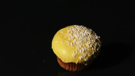 Yellow-cupcake-falling-on-black-background