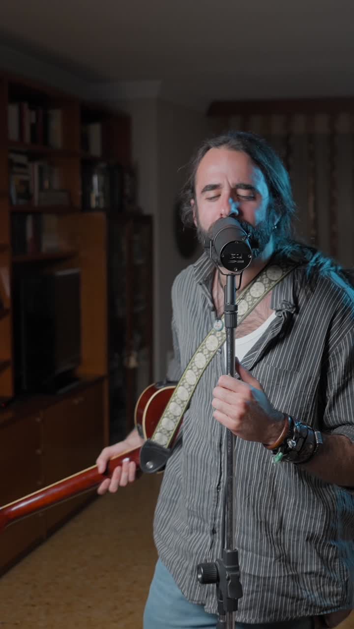 Male musician passionately singing and playing acoustic guitar in a studio