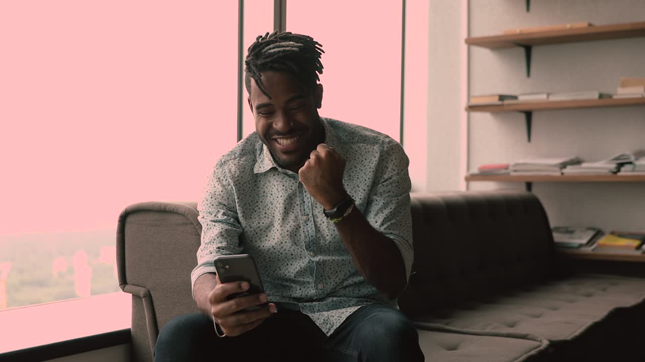 Happy african guy receive sms on smartphone celebrate great news