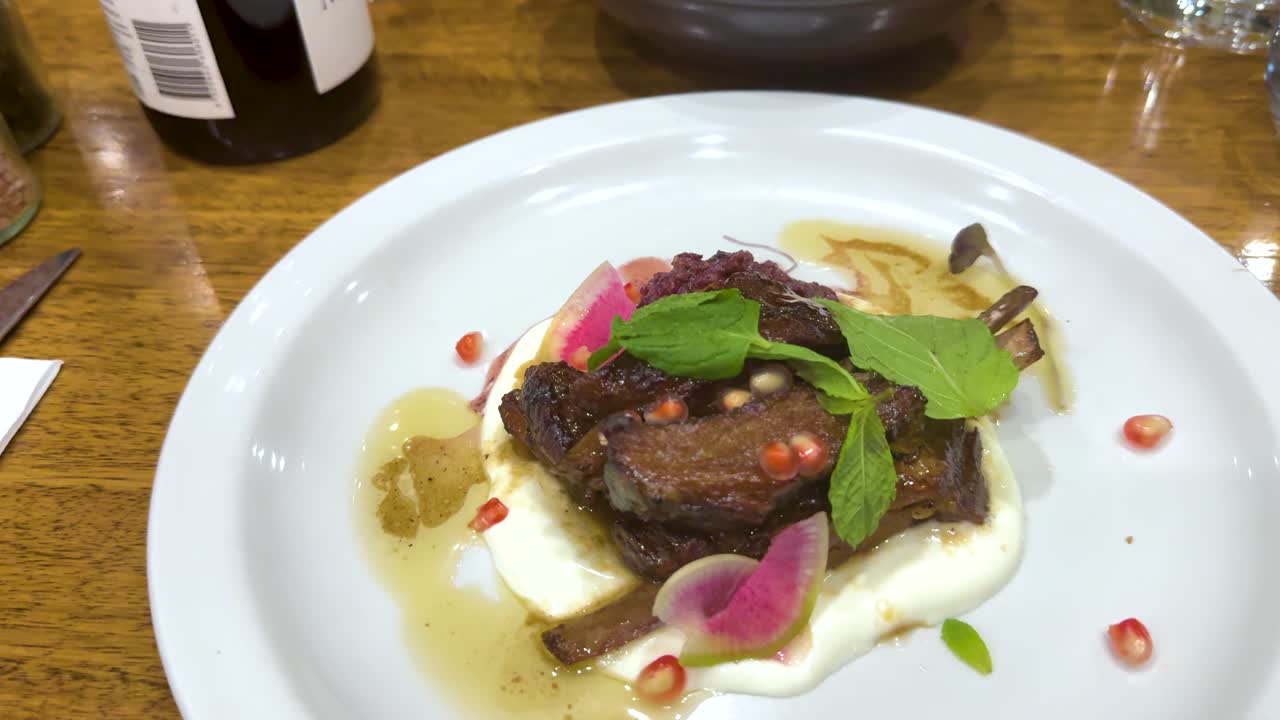 A beautifully plated rib steak with garnishes, captured in a well-lit restaurant setting, showcasing culinary artistry