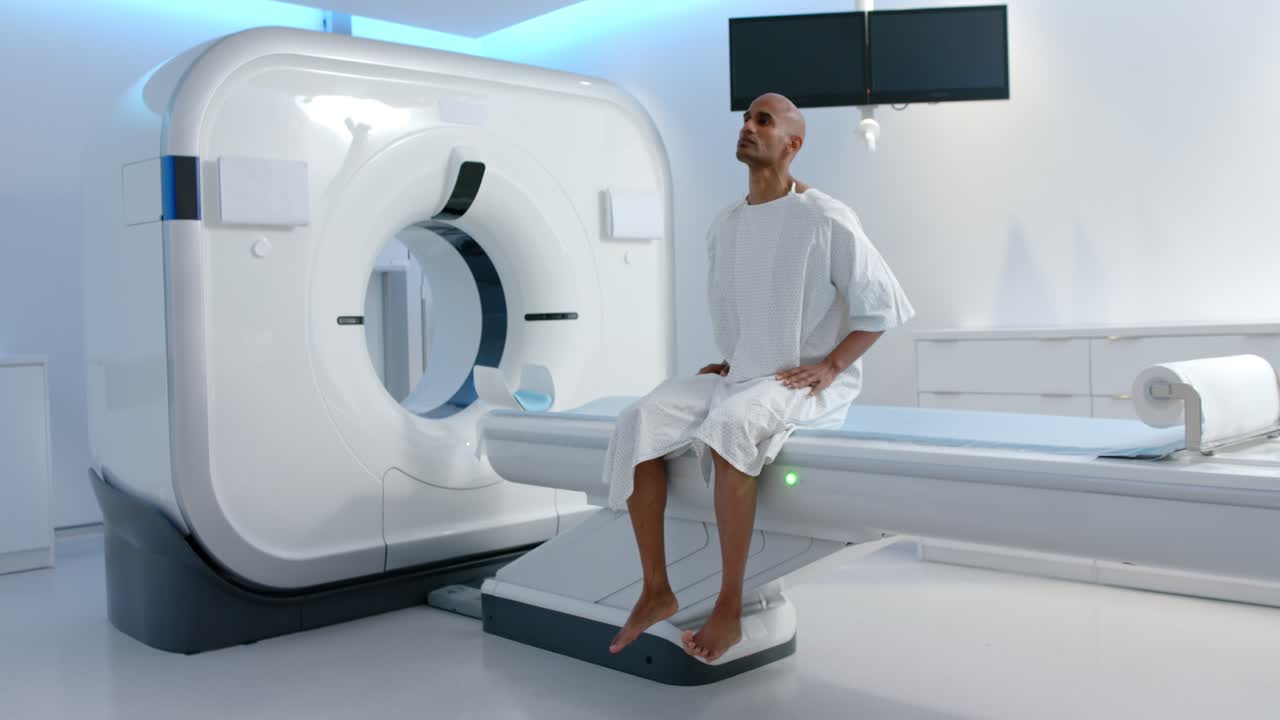 Uomo adulto di origine africana in camice su un tavolo di scanner che si prepara per una risonanza magnetica, che si sistema il collo, spazio per la copia