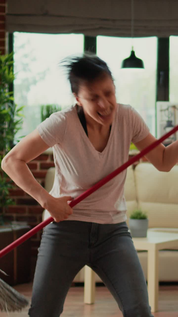Vertical video: Smiling person cleaning living room floors with mop