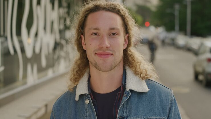 ritratto di un giovane felice che sorride guardando la telecamera godendo di uno stile di vita studentesco rilassato nella strada della città urbana serie di persone reali