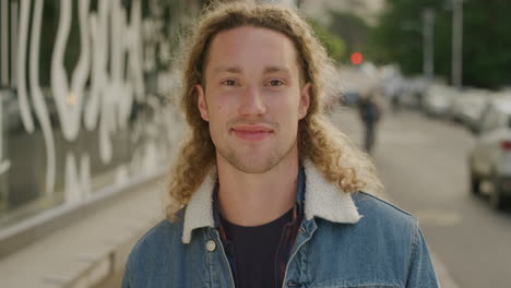 portrait of happy young man smiling looking at camera enjoying relaxed student lifestyle in urban city street real people series