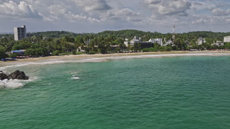 Mirissa-Sri-Lanka-Vista-Aérea-De-La-Bahía-Con-Drones-V10-Que-Captura-Una-Hermosa-Playa-De-Arena,-Aguas-Cristalinas,-Hoteles-Frente-Al-Mar-Y-Vistas-De-La-Ciudad-Costera-De-Udupila---Filmada-Con-Cine-Mavic-3---Abril-De-2023