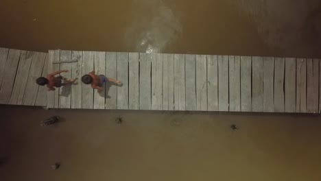 aerial view of a group of warao indigenous children running in a river wooden pier