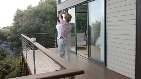 Happy-diverse-gay-male-dancing-on-balcony-at-home,-slow-motion