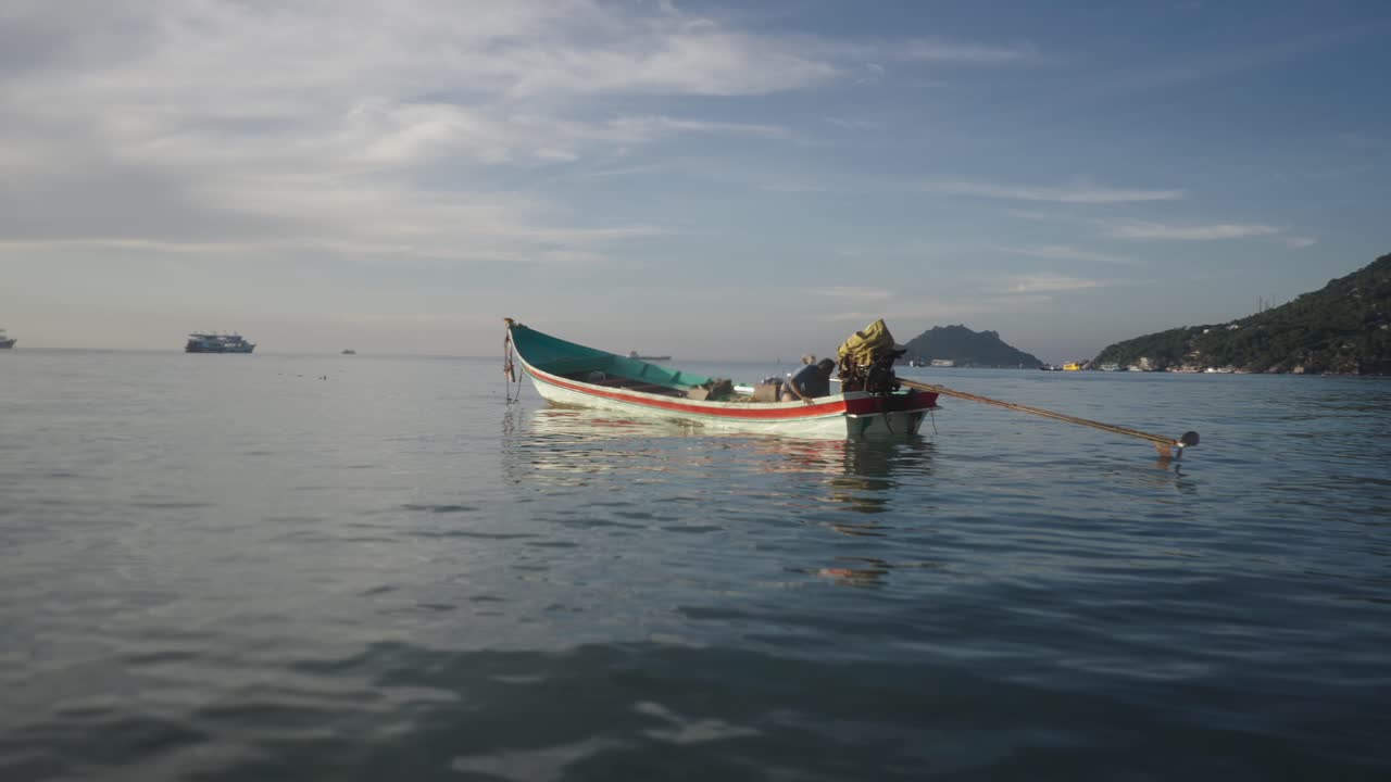 A person on a traditional longtail boat in calm tropical waters