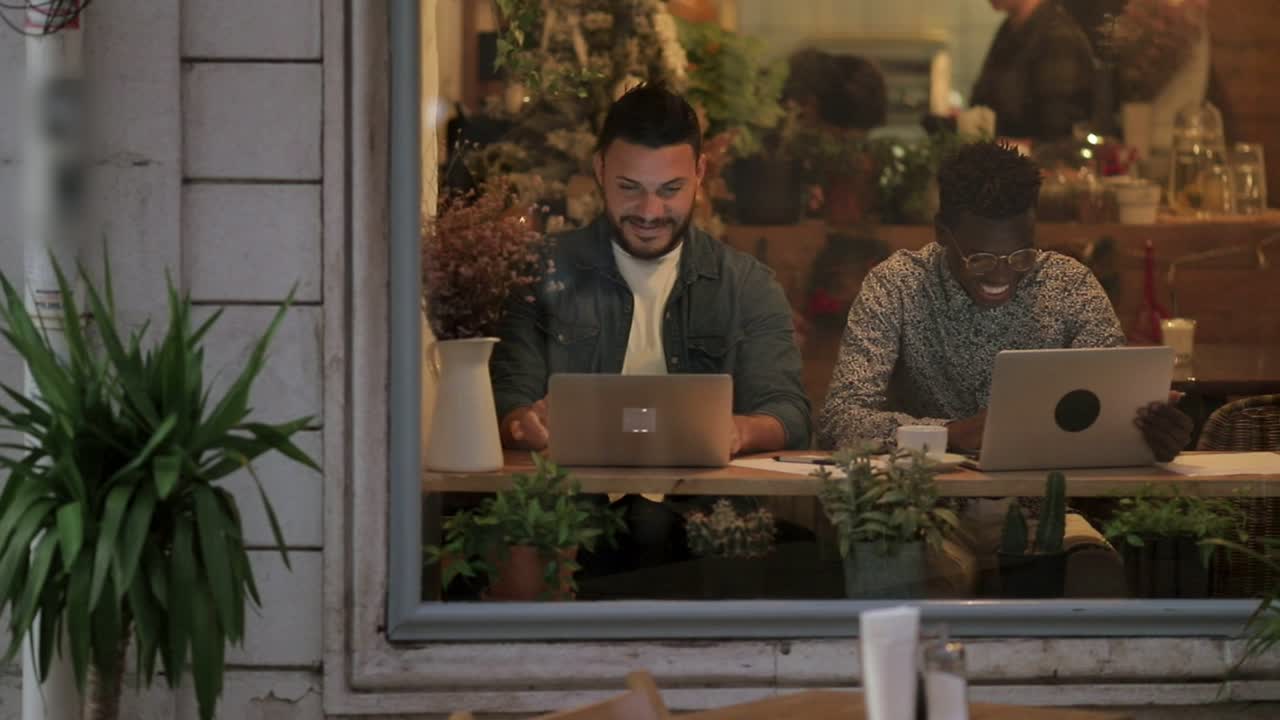 Happy freelancers using laptops in coffee shop