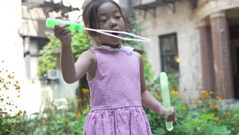 Oriental-little-girl-blowing-bubbles-in-the-courtyard,-body-close-up-with-copy-space