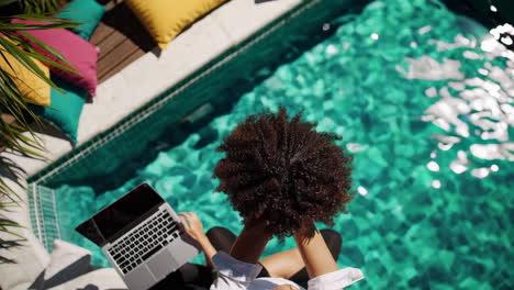 woman stretching poolside with laptop