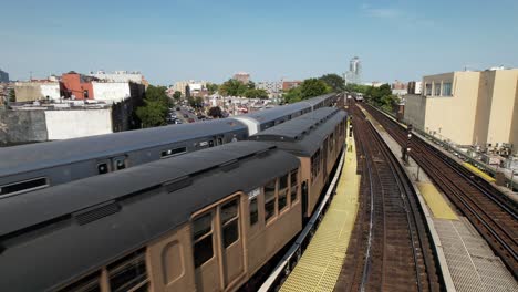 una vista aérea de vías elevadas con un tren histórico que se aleja de la cámara y un tren actual, en funcionamiento en las vías exteriores