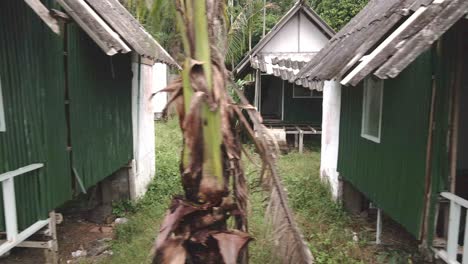 left moving trucking shot of a abandoned derelict destroyed bungalow beach resort in the tropics affected by covid tourism