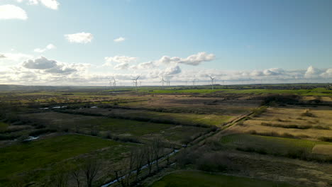 aerial wide view of wind farm in rural spring landscape during sunlight outdoors in nature