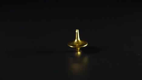 golden spinning top rotating on a black surface