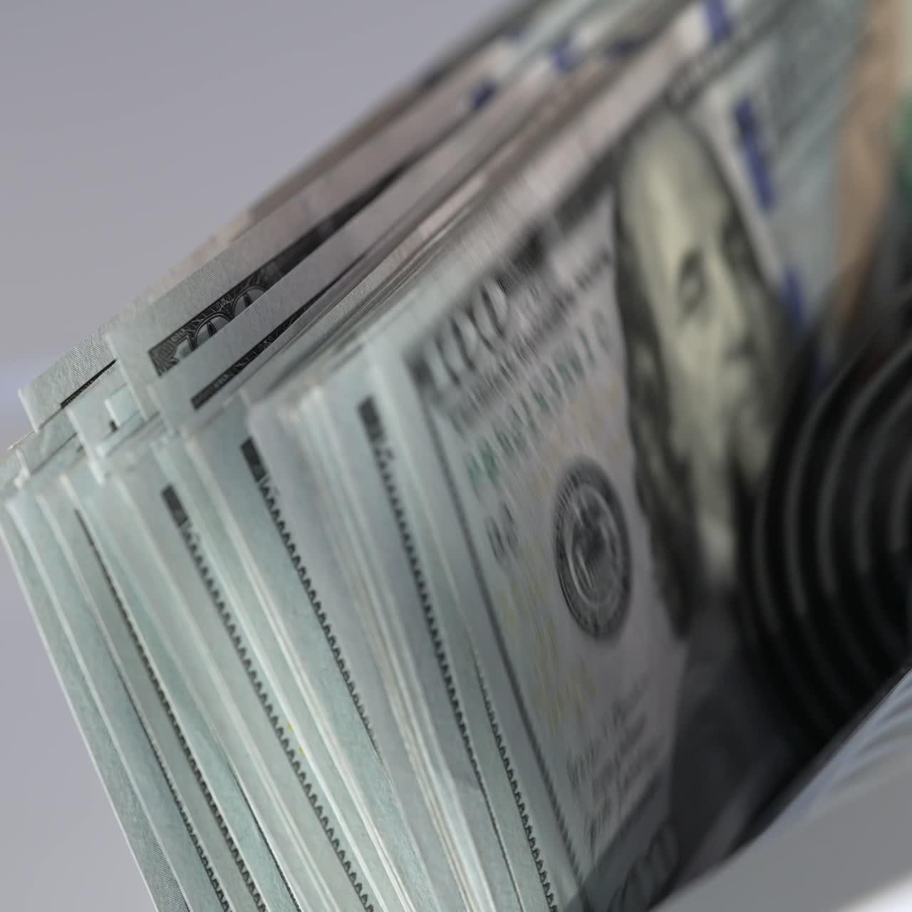 One hundred dollar banknotes falling quickly on the holder of cash machine. US currency counted in the special equipment. Close up