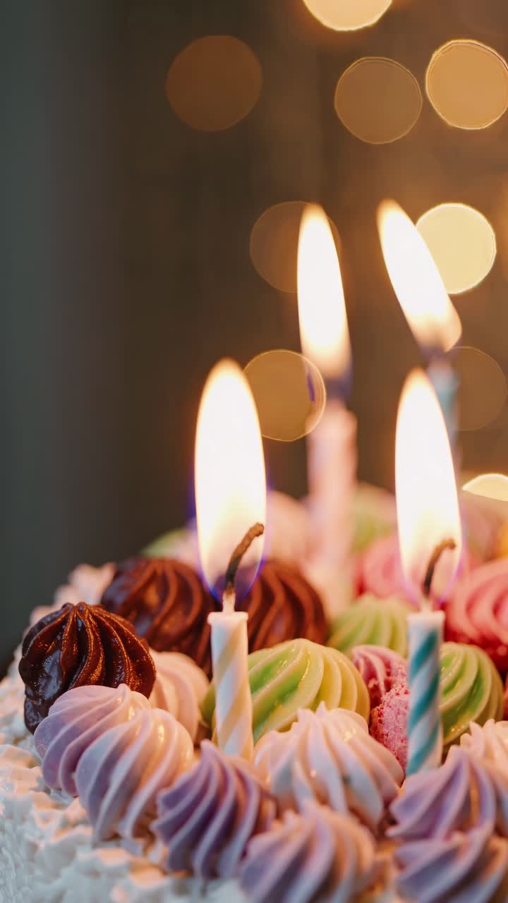 Close-up video of a colorful birthday cake with lit candles, shot from a low angle