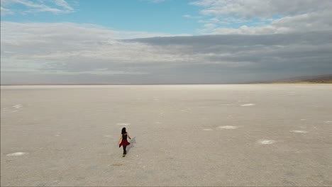 Flying-over-a-girl-walking-on-the-pink-salt-lake,-the-largest-dry-lake-in-Turkey-and-one-of-the-largest-salt-lakes-the-world