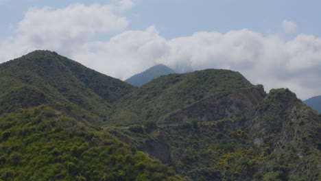 Stationary-time-lapse-shot-of-huge-mountains-with-white-fluffy-clouds-moving-over-them-located-in-Echo-Mountain-Trails-California