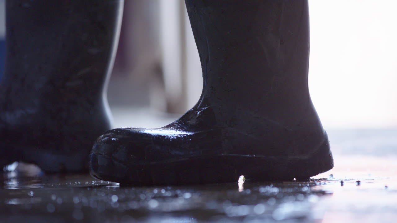 SLOW MOTION - liquid splashes around rubber boots on a concrete floor