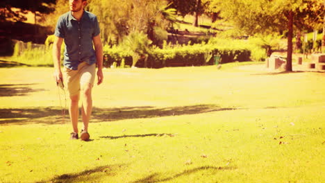 Un-Hombre-Guapo-Caminando-Por-El-Parque-Y-Sosteniendo-Una-Cámara-De-Fotos-Retro.