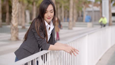 Relaxed-thoughtful-young-woman-leaning-on-railings