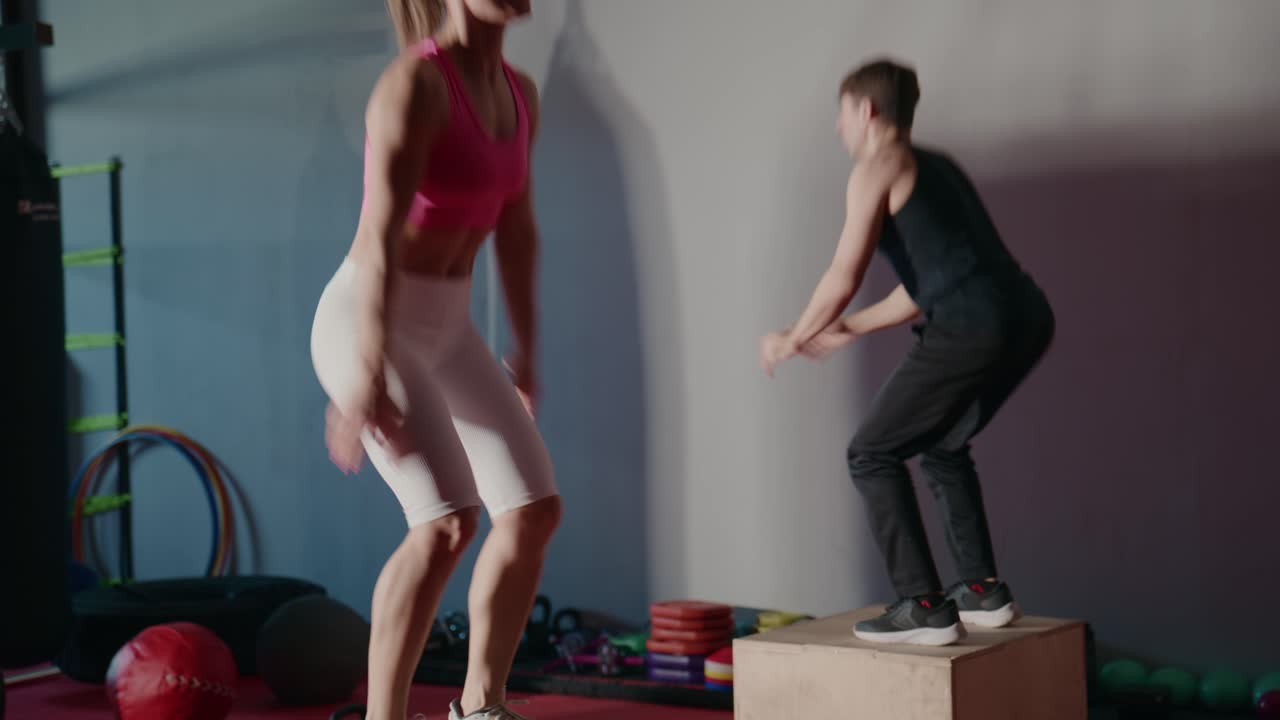 Coppia atletica che esegue box jumps in palestra