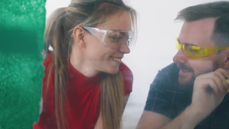 couple in goggles paints wall with bright colors in room