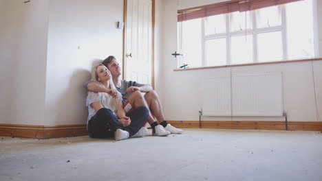 pareja sentada en el suelo en una habitación vacía de nuevo diseño de planificación de la casa