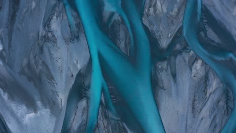 top down aerial shot of blue glacial braided river delta that looks like abstract art, godley river, new zealand