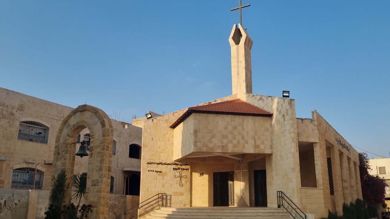 A luz do sol do entardecer ilumina a Igreja Cristã Moderna, também conhecida como Igreja do Nazareno, na Rua da Palestina em Madaba, Jordânia, destacando sua arquitetura moderna e luz acolhedora