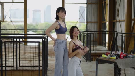 two women posing and smiling in a casual indoor setting