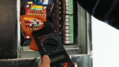 electricians hands testing current  electric in control panel. electrician engineer work  tester measuring  voltage and current of power electric line in electical cabinet control.