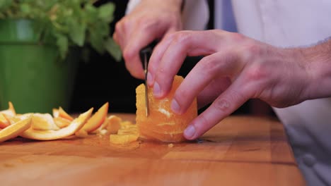 Der-Koch-Schneidet-Die-Orange-Auf-Einem-Holzbrett