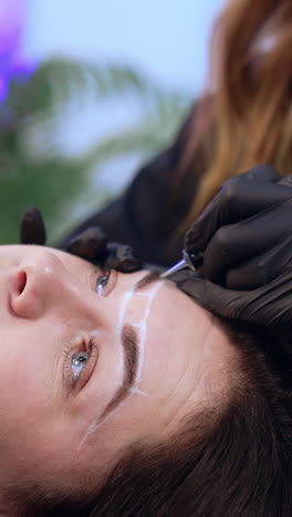 beautiful adult lady is a client of brow master. client having the permanent make up procedure for eyebrows. close up. vertical video