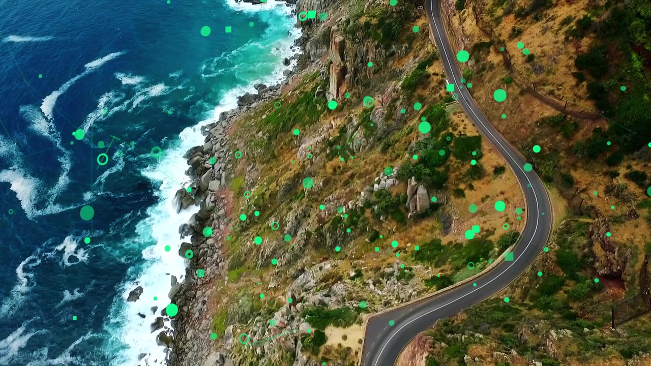 Oblique cam starting drift, cliff road revealing more shore; green graphics shifting over sea, land