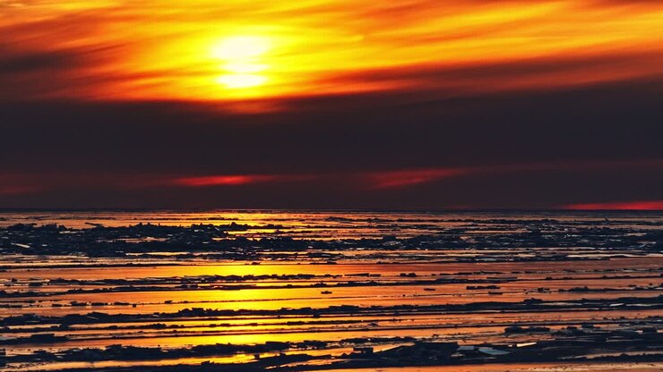 Arctic view with frozen sea and ice floes at sunset with colorfuls sky, natural northern background in cold climate