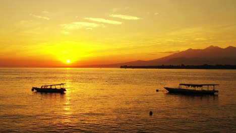 bahamas, golden sunset over the calm tropical sea with fishing boats and mountains in the horizon