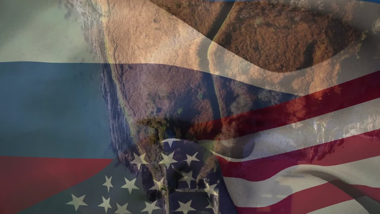 Vento a raffiche, bandiera tricolore che sventola, costa che sfuma, bandiera statunitense che si fonde, creando un montaggio con un veicolo.