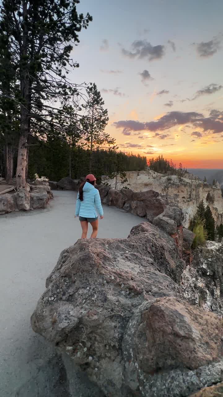 mujer joven en el punto de vista al atardecer, gran cañón del parque nacional de yellowstone, wyoming estados unidos