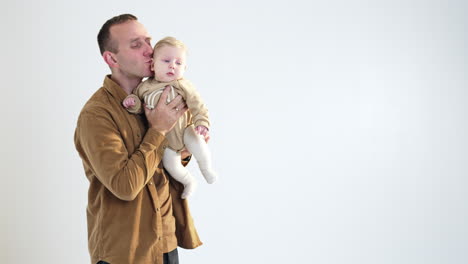 loving dad holds his cute blond baby boy. long-haired lady comes up bringing a cake. family celebration. white backdrop.