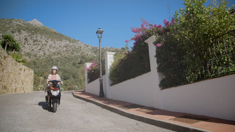 Mujer-Conduciendo-Cuesta-Abajo-En-Scooter-Con-La-Montaña-De-La-Concha-En-Segundo-Plano.