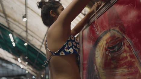 in this middle slowmotion shot, a young girl carefully hangs art canvases at a local art gallery, showcasing her commitment to creating a visually captivating exhibition