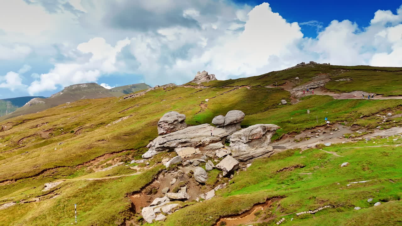 Eroded rock formations on Bucegi Plateau. Unique eroded stone formations standing on the green slopes of Bucegi Plateau
